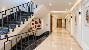 Un interior moderno con una escalera de mármol, un pasillo con obras de arte enmarcadas y un suelo pulido.