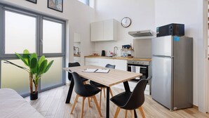 Une cuisine moderne avec un coin repas, un réfrigérateur et une plante en pot.