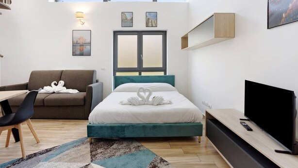 Une chambre d’hôtel moderne équipée d’un lit, d’un canapé, d’un bureau et d’une télévision.