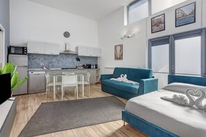 A modern apartment with a kitchen, dining area, and a bedroom.