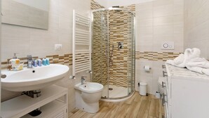 Une salle de bain moderne avec une douche à parois de verre, un lavabo blanc et un bidet.