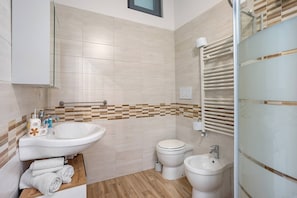 Un bagno moderno con lavandino, toilette, bidet e porta asciugamani.