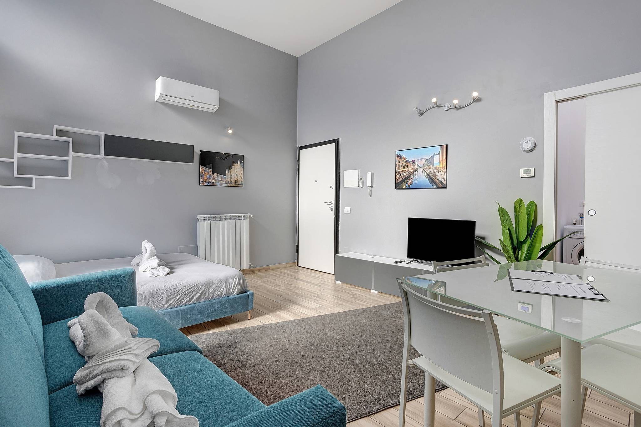Ein modernes Hotelzimmer mit einem Bett, einem Schreibtisch, einem Stuhl, einem Heizkörper und einem Fernseher.