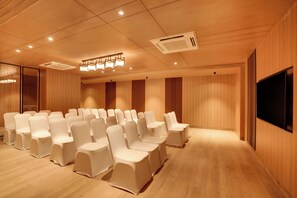 A conference room with rows of chairs, a large screen, and a ceiling light fixture. - Keys Prima by Lemon Tree Hotels, Nashik (Nashik)