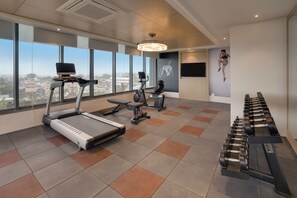 Un gimnasio con cintas de correr, bicicletas estáticas y mancuernas.