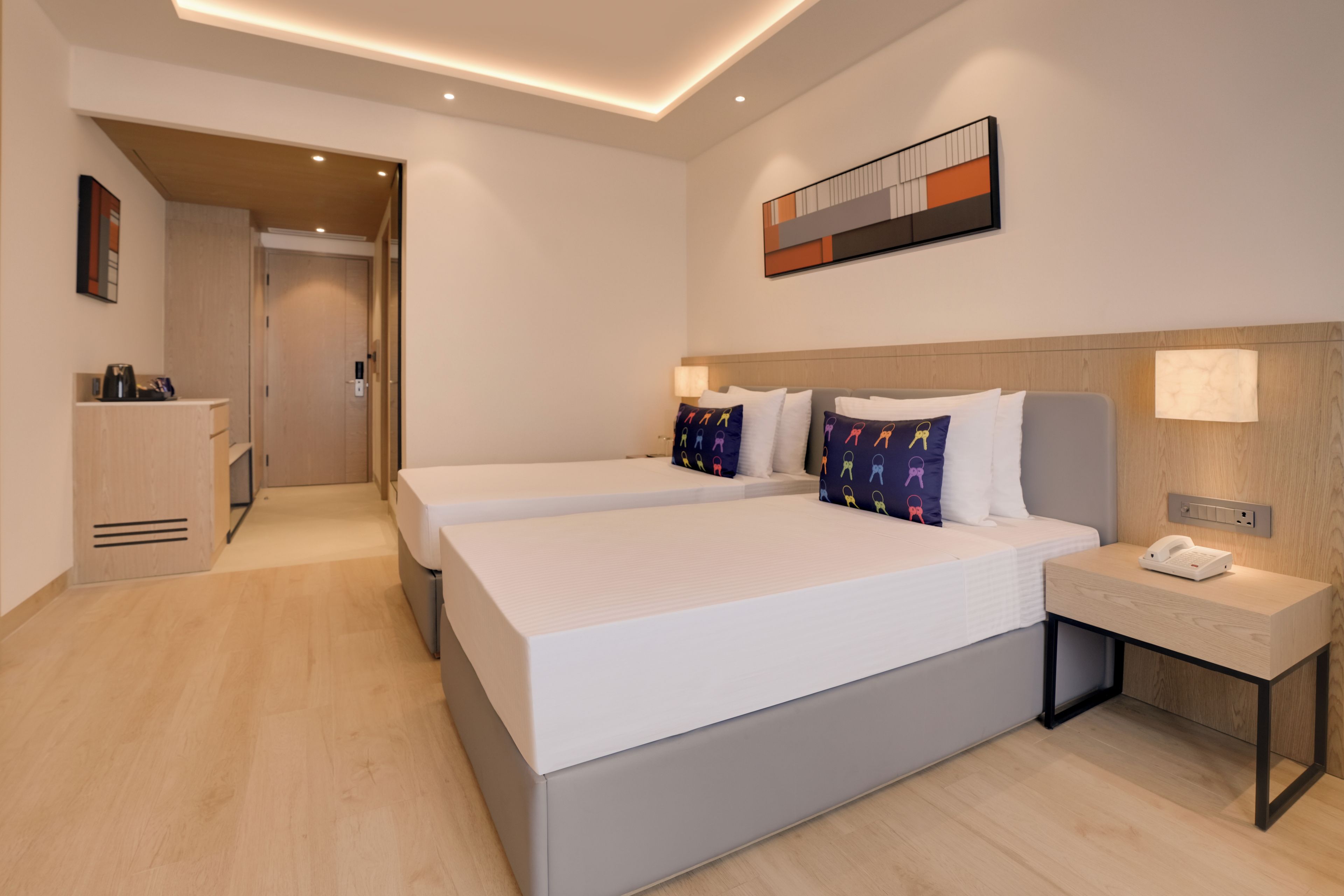 Une chambre d’hôtel moderne avec un grand lit, des tables de chevet et un petit bureau avec un téléphone.