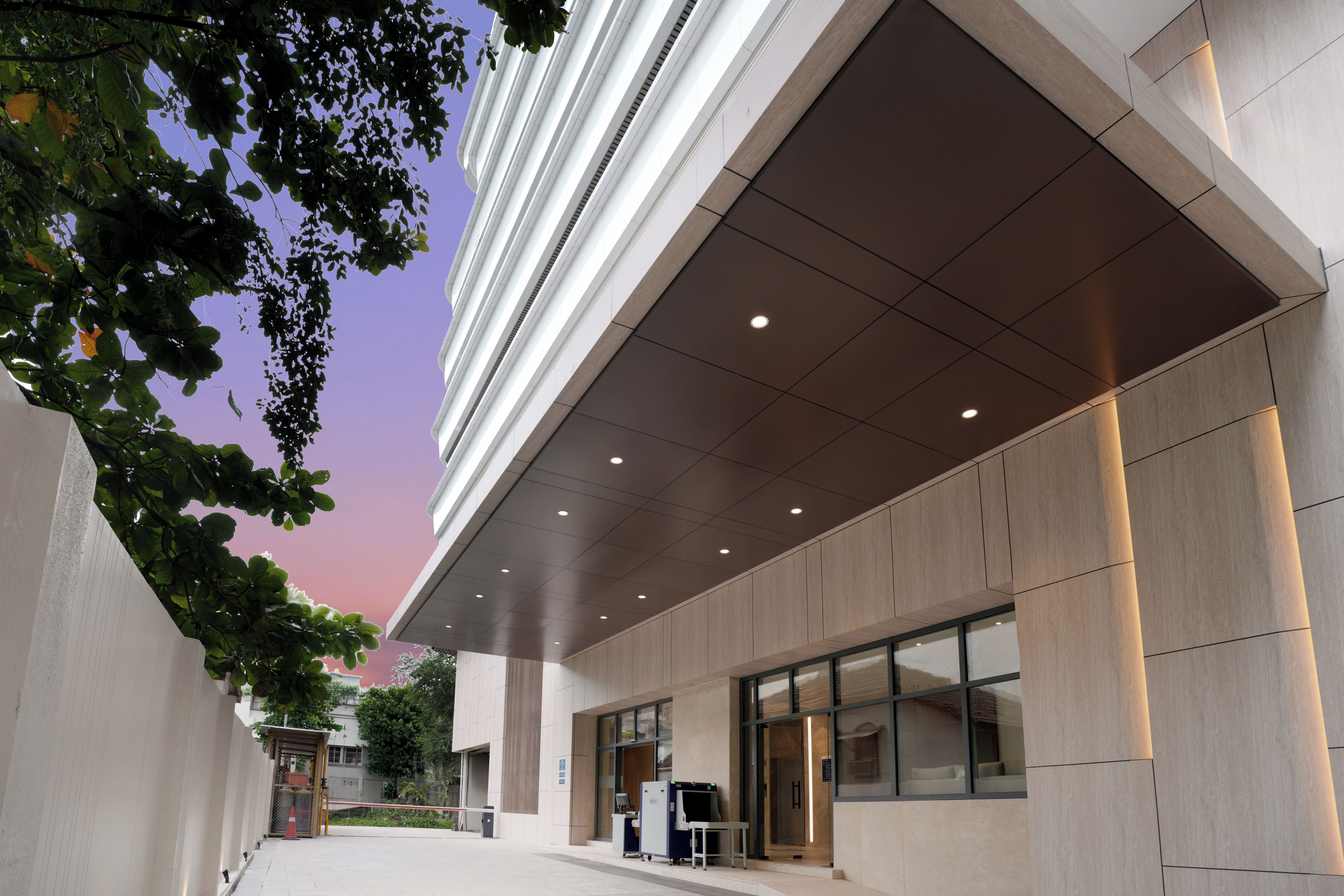 A modern building with a covered entrance, a glass door, and a security kiosk.