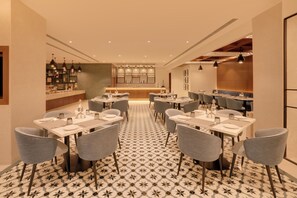 Un restaurante con varias mesas, sillas y una zona de bar.