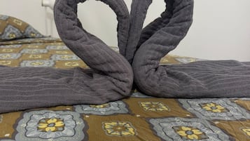 Un lit avec une couvre-lit à motifs et une serviette disposée en forme de cœur.