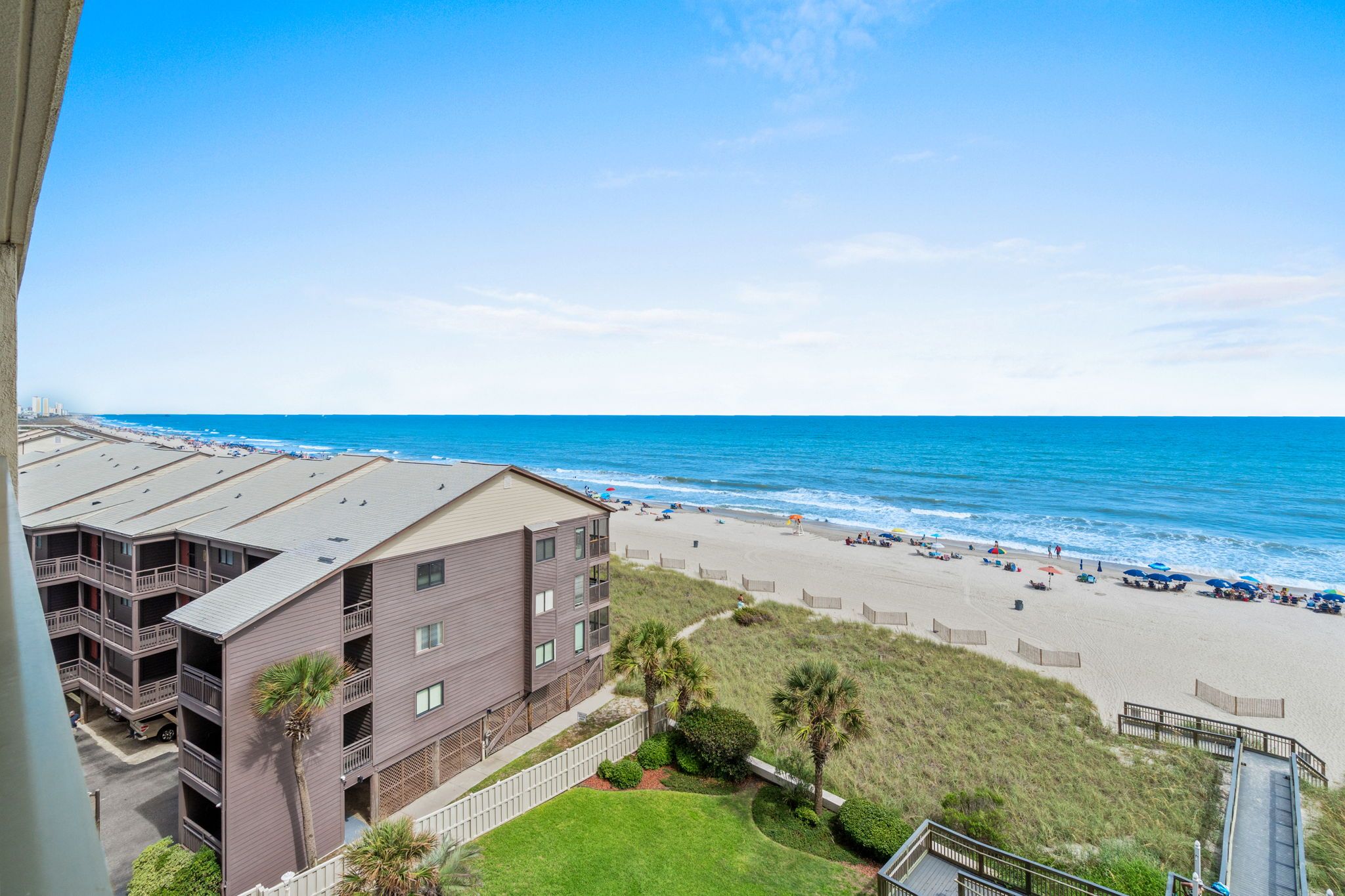 Un hotel frente al mar con varios balcones, una playa de arena y el océano.