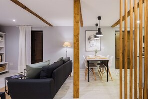 A modern living room with a sofa, a dining table with chairs, and a lamp.