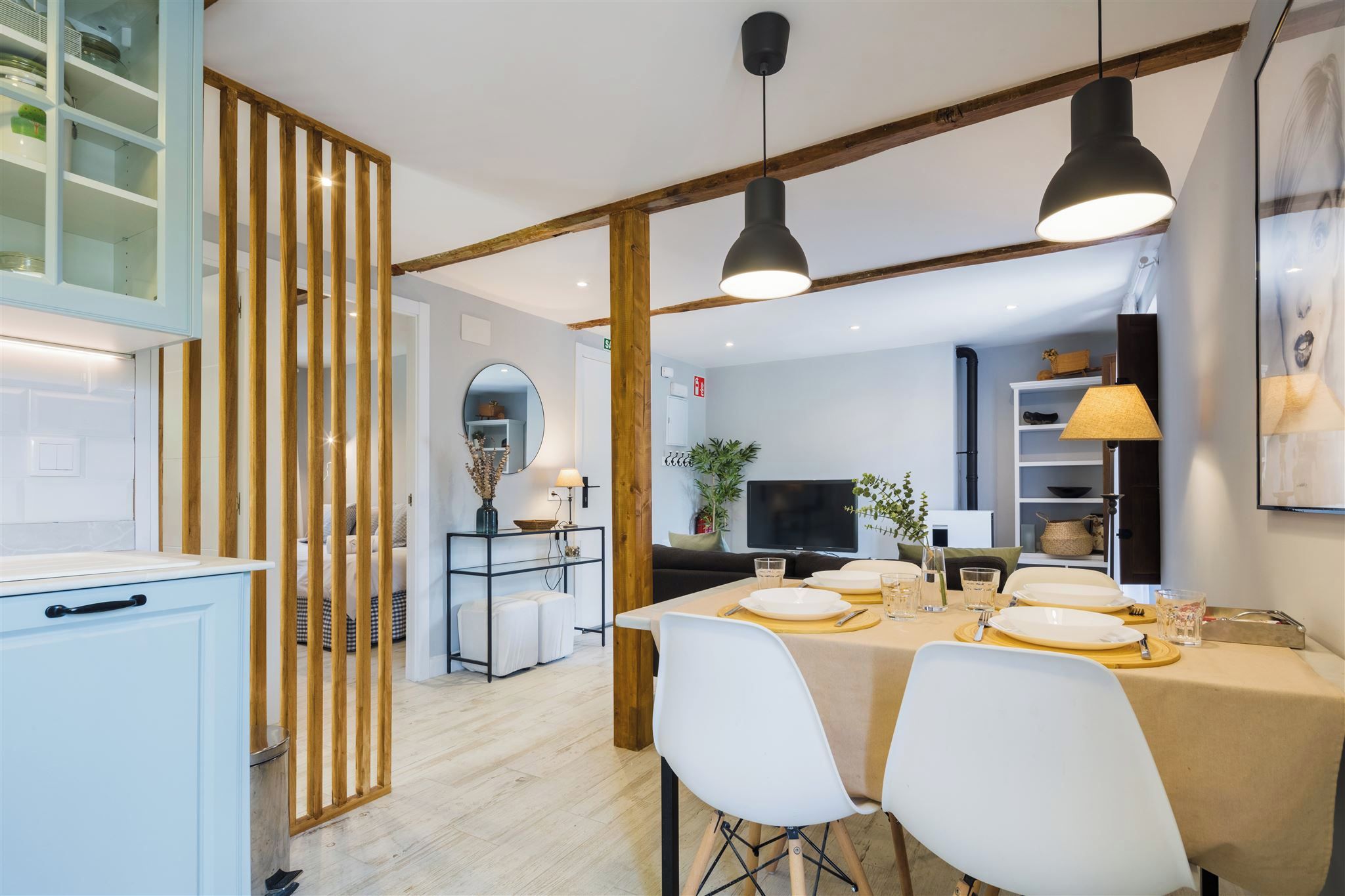 A modern kitchen with a dining area, wooden beams, and pendant lighting.