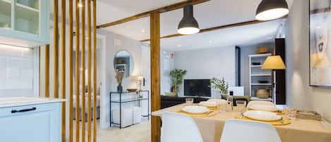A modern kitchen with a dining area, wooden beams, and pendant lighting.