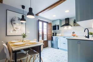 A modern kitchen with a dining area, featuring pendant lights, a large window, and a kitchen island. - Comfortable Apartment in a Traditional Asturian House in the Aller Valley (Cabañaquinta)