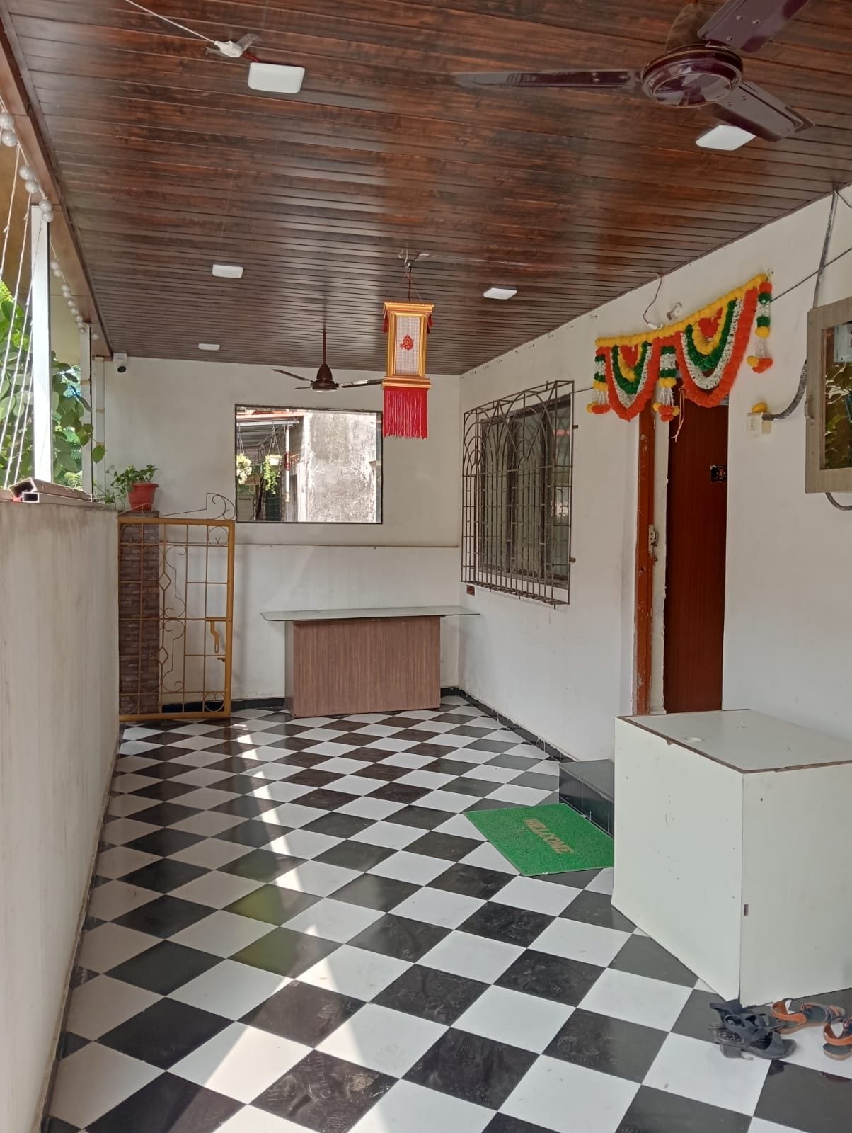 Quarto com chão quadriculado, ventilador de teto, janela e porta.