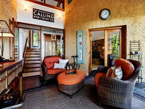 A cozy living area with a staircase, wicker furniture, and a clock on the wall. - Merryland with Wintergreen Advantage (Wintergreen)