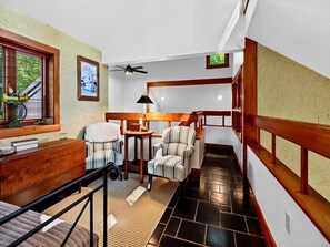 A room with a bed, a chair, a table, a lamp, and a staircase with wooden railings. - Merryland with Wintergreen Advantage (Wintergreen)