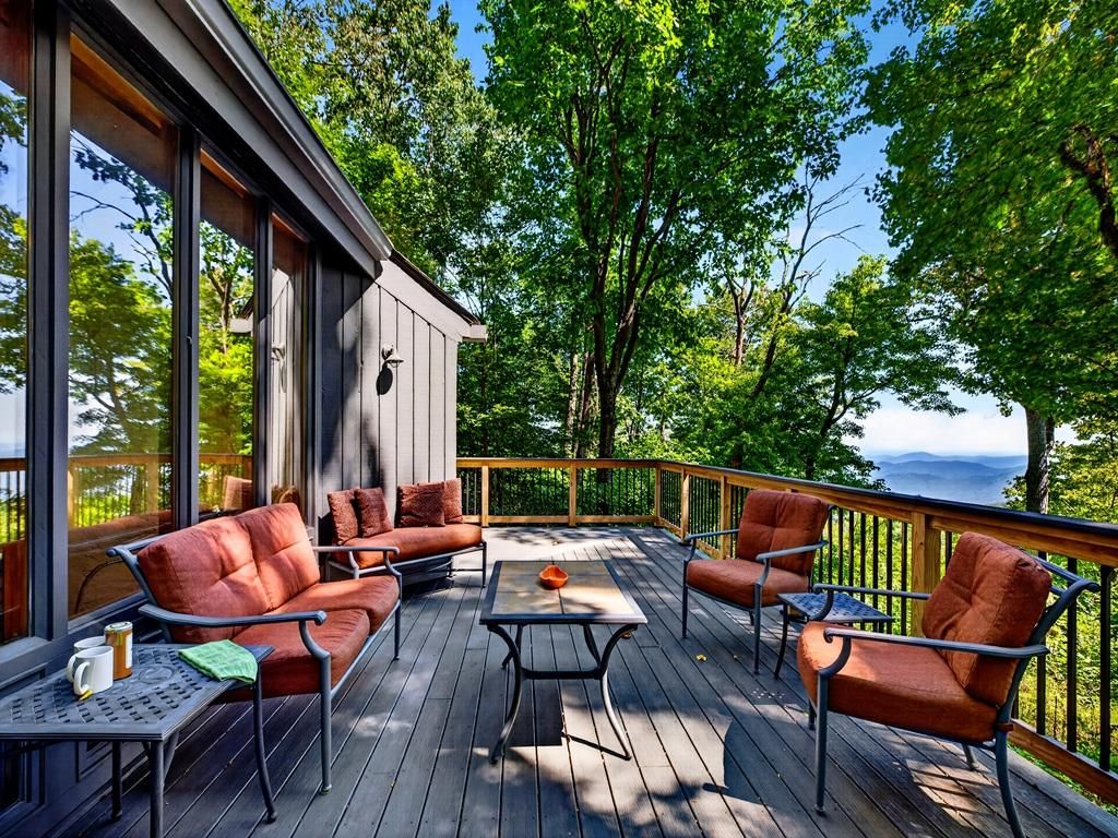 A deck with outdoor furniture, a table, and a view of the surrounding nature.