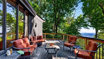 A deck with outdoor furniture, a table, and a view of the surrounding nature.