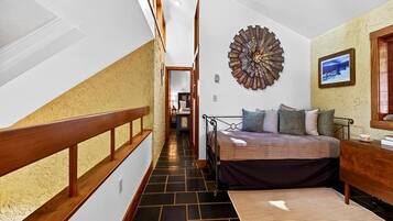 A bedroom with a bed, a wooden headboard, a large wall clock, and a view of a hallway.
