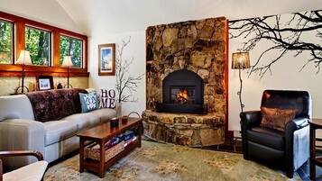 A living room with a stone fireplace, a sofa, a chair, and a rug.