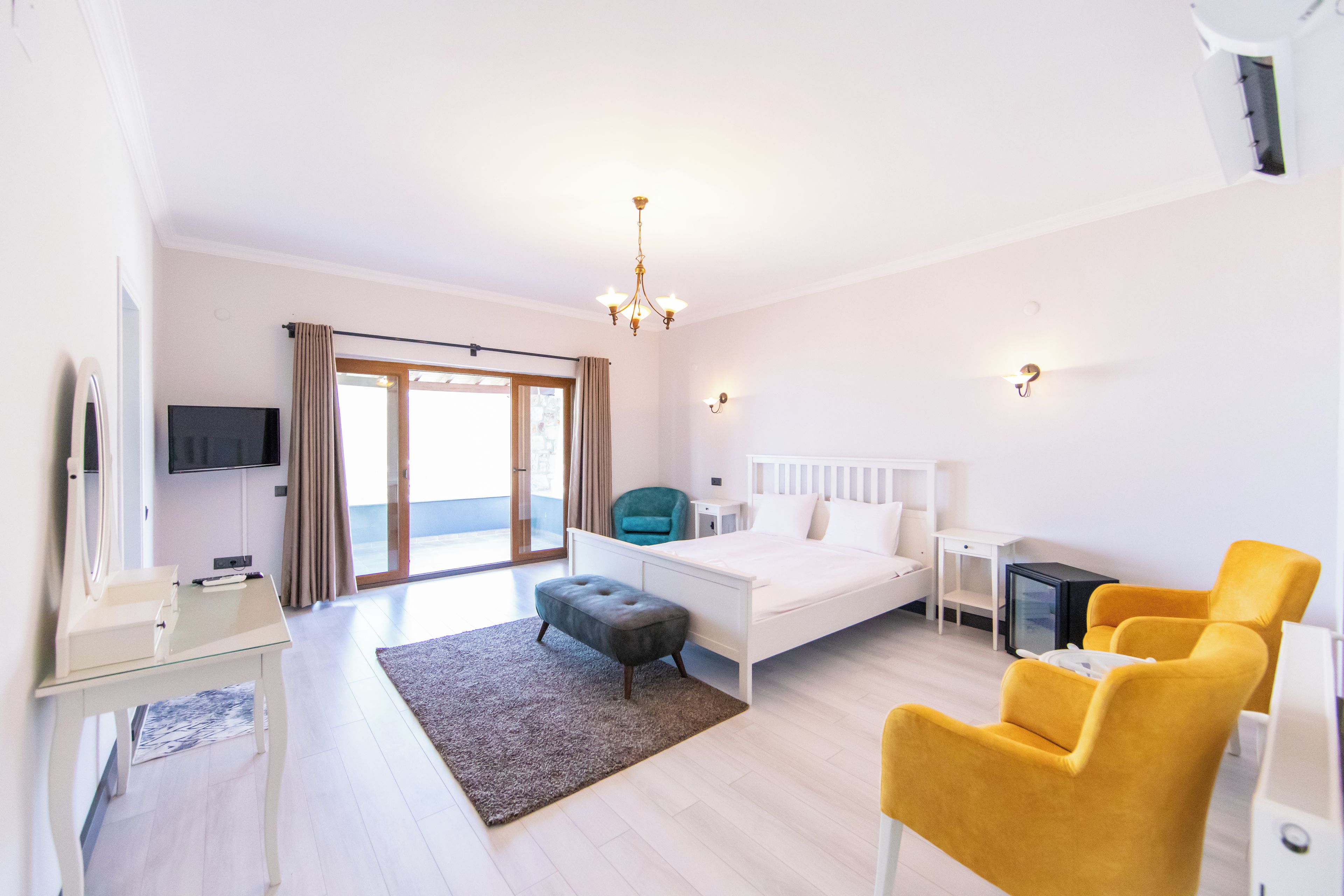 Una habitación de hotel con cama, escritorio, silla, televisión y vistas al exterior.