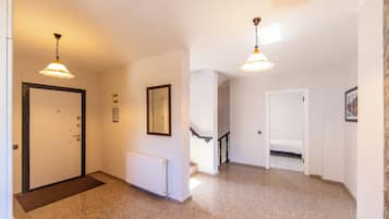 Un pasillo con una puerta, un radiador, un cuadro enmarco y una escalera que sube a otra habitación.