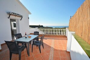 Una terraza con una mesa y sillas, una botella de vino y vistas al mar.