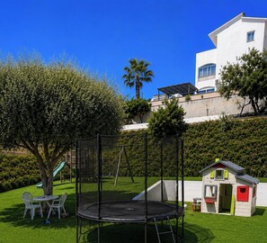 Ein Spielplatz mit Trampolin, Rutsche und einer kleinen Spielhütte.