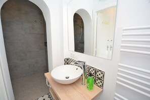 Un baño con un lavamanos blanco, un espejo y una ducha.