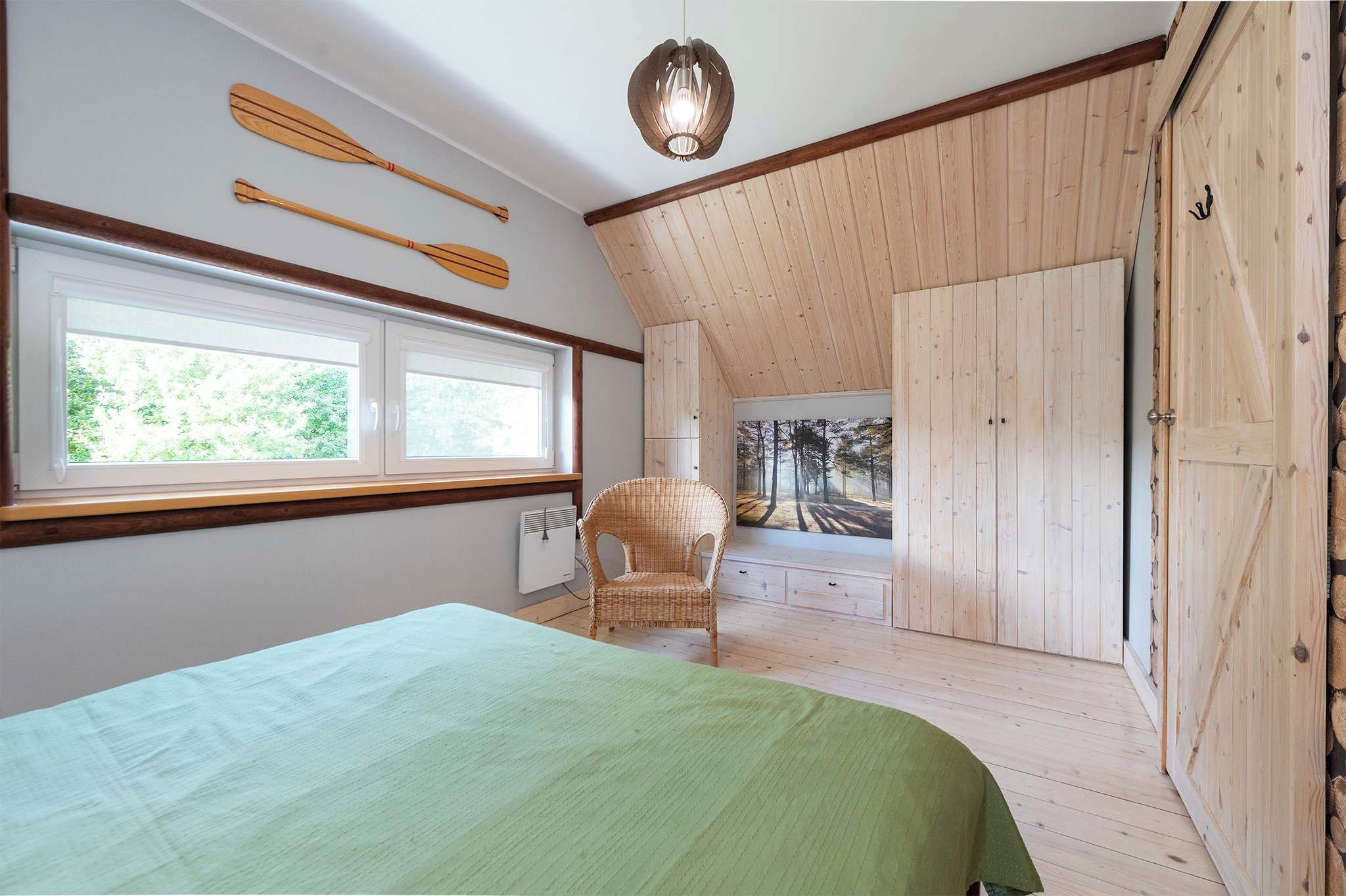 Une chambre à coucher avec un lit, une chaise, des murs en bois, une fenêtre et une porte.