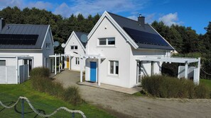 Une rangée de maisons modernes dotées de panneaux solaires, aux façades blanches, sous un ciel dégagé.