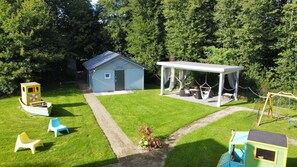 Ein Garten mit Spielhaus, Schaukel und kleiner Gartenhütte.