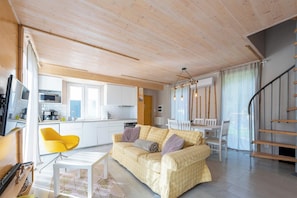 Ein stilvoller Wohnraum mit Sofa, einem gelben Sessel, einem Esstisch und einer Küchenzeile.
