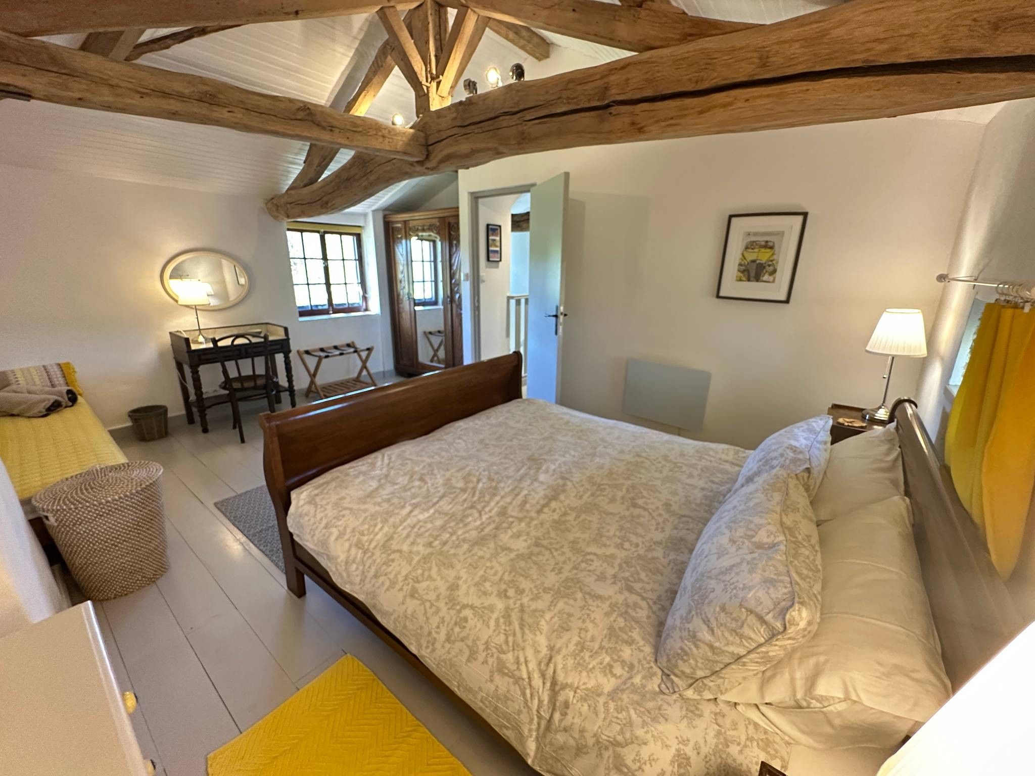Quarto com uma cama grande, uma escrivaninha e uma cadeira.