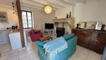 A living room with a fireplace, a television, a sofa, and a kitchen area.