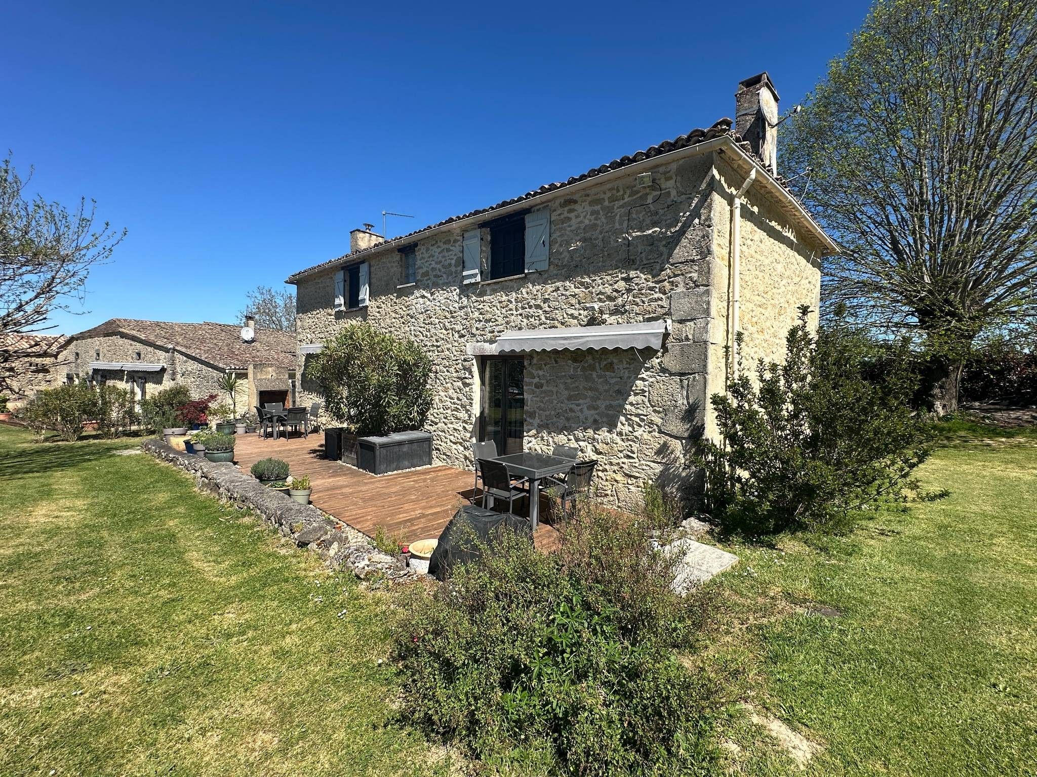 Une maison en pierre dotée d’une terrasse et d’un espace extérieur aménagé pour s’asseoir.