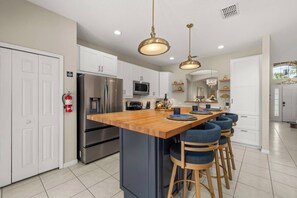 A modern kitchen with a central island, stainless steel appliances, and pendant lighting. - 6BR Aviana Resort Escape | Pool, Spa + Game Room (Davenport)