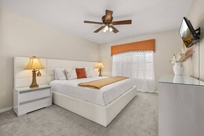 A bedroom with a bed, bedside tables, a ceiling fan, a TV, and a window with curtains. - 6BR Aviana Resort Escape | Pool, Spa + Game Room (Davenport)
