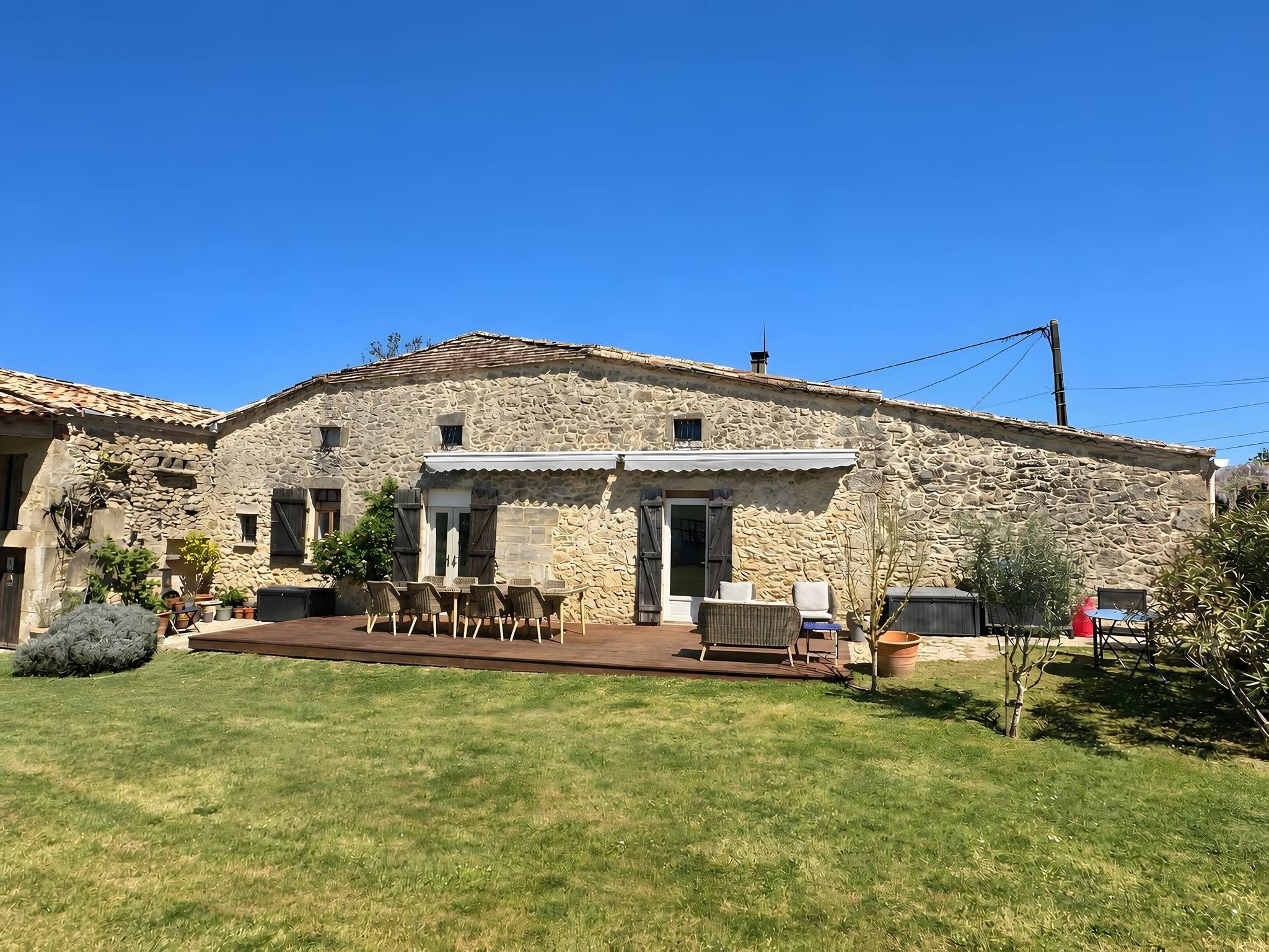 A stone building with a patio area, outdoor seating, and a clear blue sky.