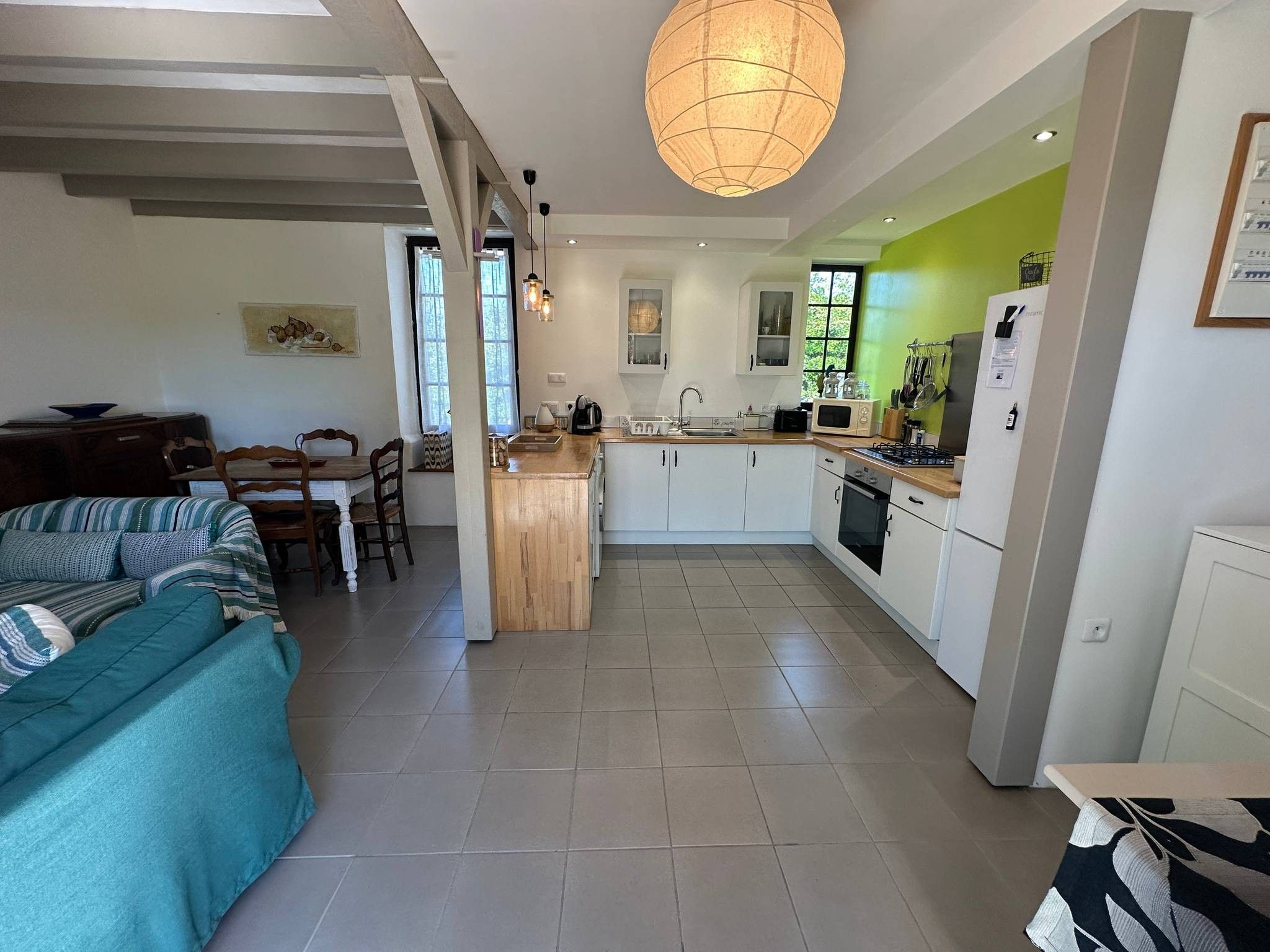 A modern kitchen with white cabinets, a central island, and a dining area with a sofa and chairs.