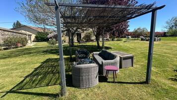 Ett takförsett utomhusområde med sittplatser, möbler av rotting och en pergola.