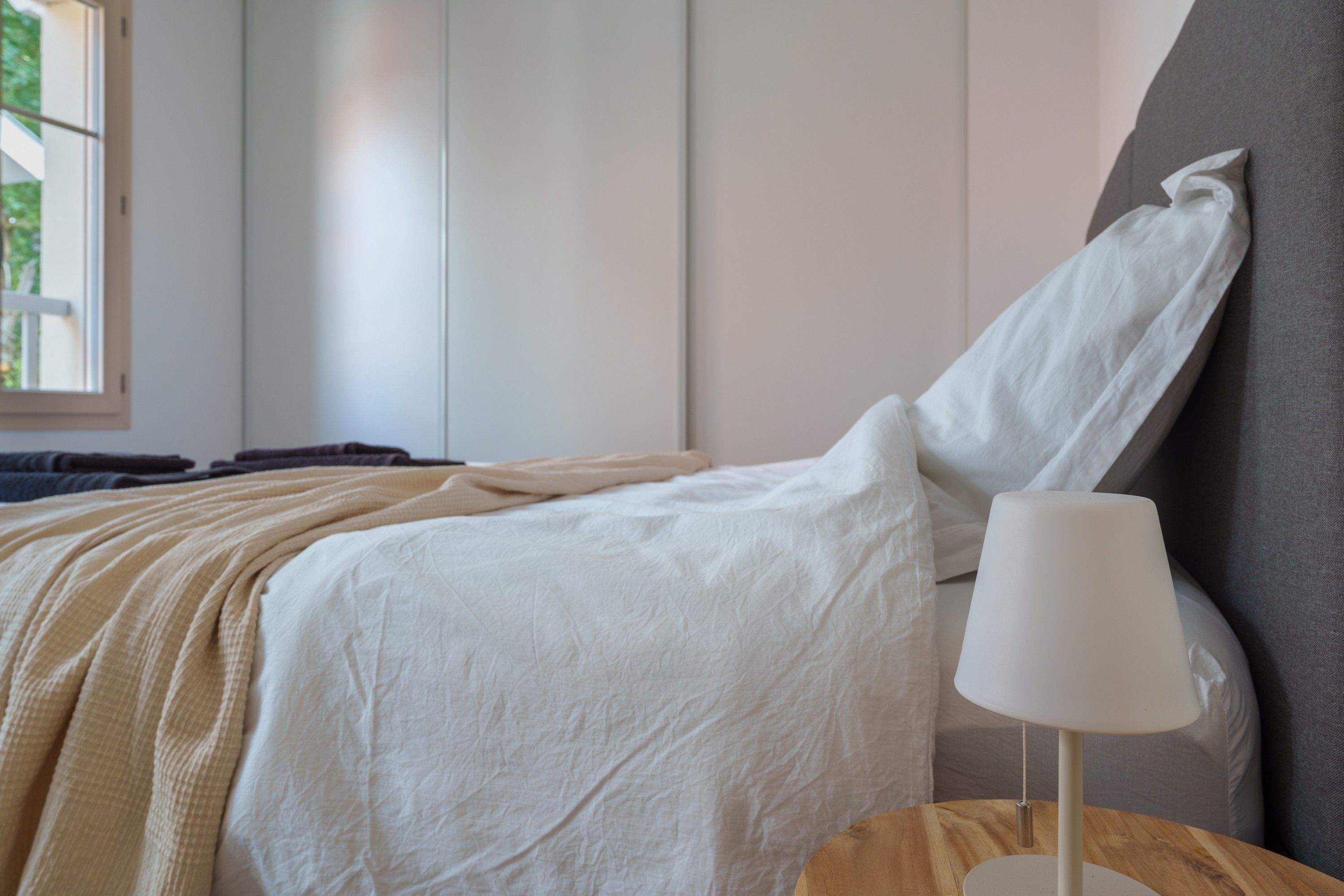 A bedroom with a bed, a bedside lamp, and a window.
