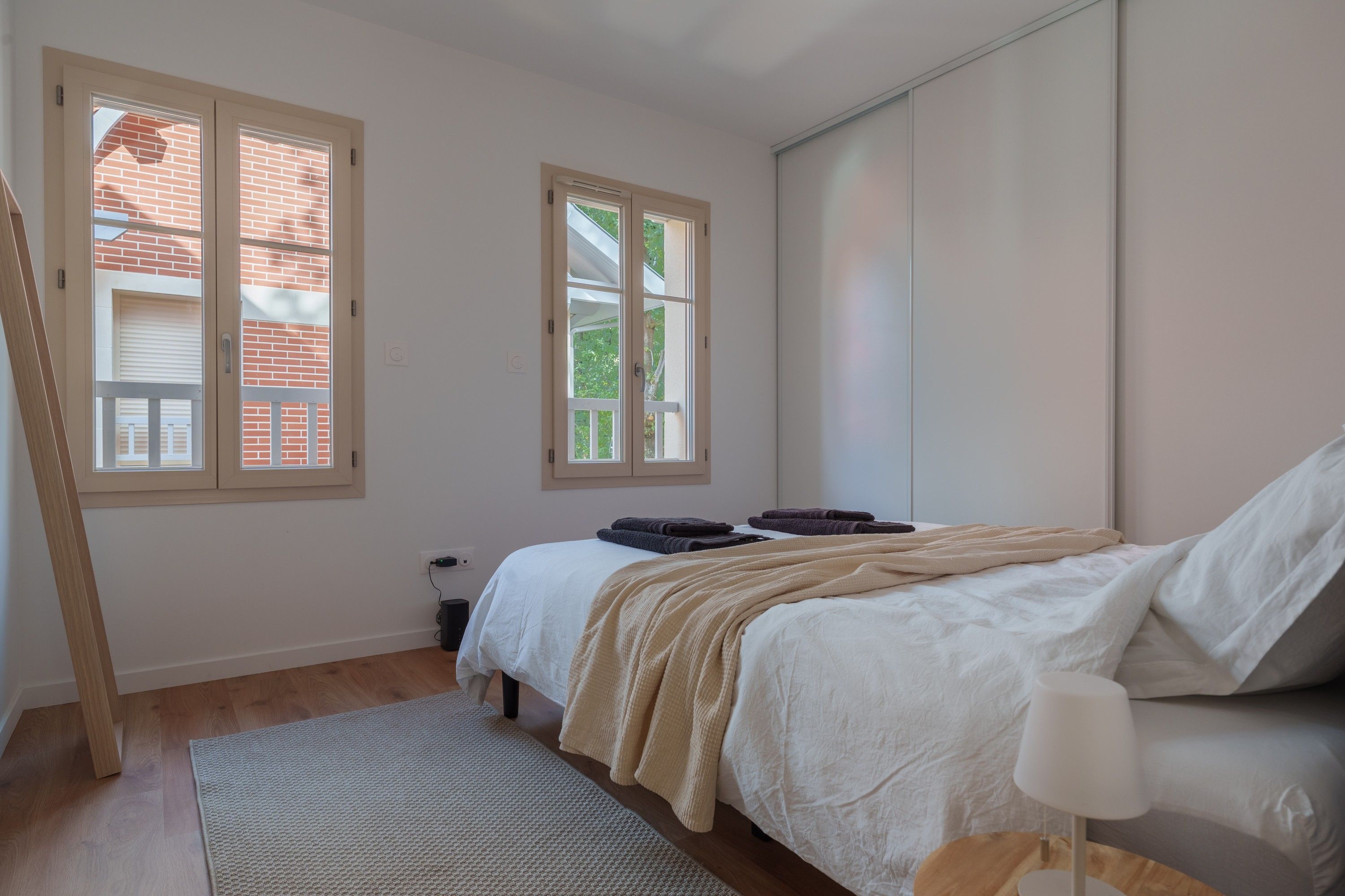Ein Schlafzimmer mit einem Bett, einem Nachttisch, einer Lampe, einem Fenster und einer Heizung.