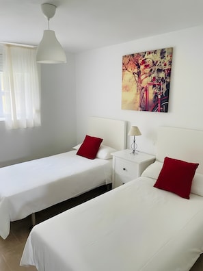 Habitació d'hotel amb dos llits, una petita taula de nit, una làmpada i un quadre a la paret.