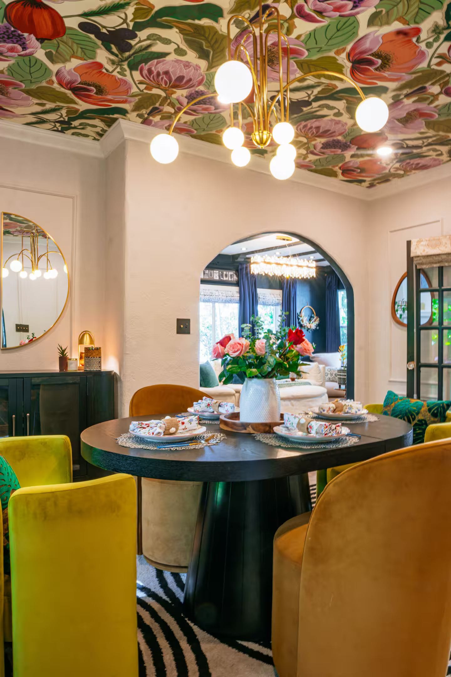 Un comedor con una mesa redonda, sillas y un diseño floral en el techo.