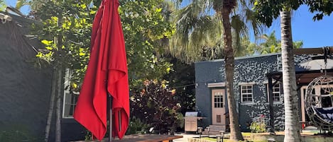 An outdoor patio area with picnic tables, a red umbrella, and a building with a stone facade.