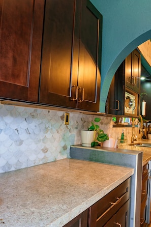 A kitchen with dark wooden cabinets, a tiled backsplash, and a granite countertop. - Art Deco Designer Home + Jacuzzi, Walk to Beach (Hollywood)