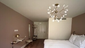 Une chambre à coucher avec un grand lit, une table de chevet, une lampe et un luminaire au plafond.