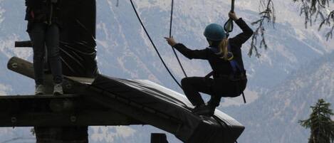 A zip-lining activity with participants on a platform and a mountainous backdrop.